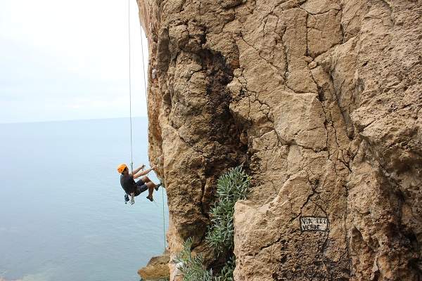 man rappelling on a cliff