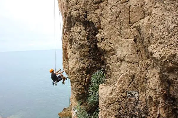 man rappelling on a cliff